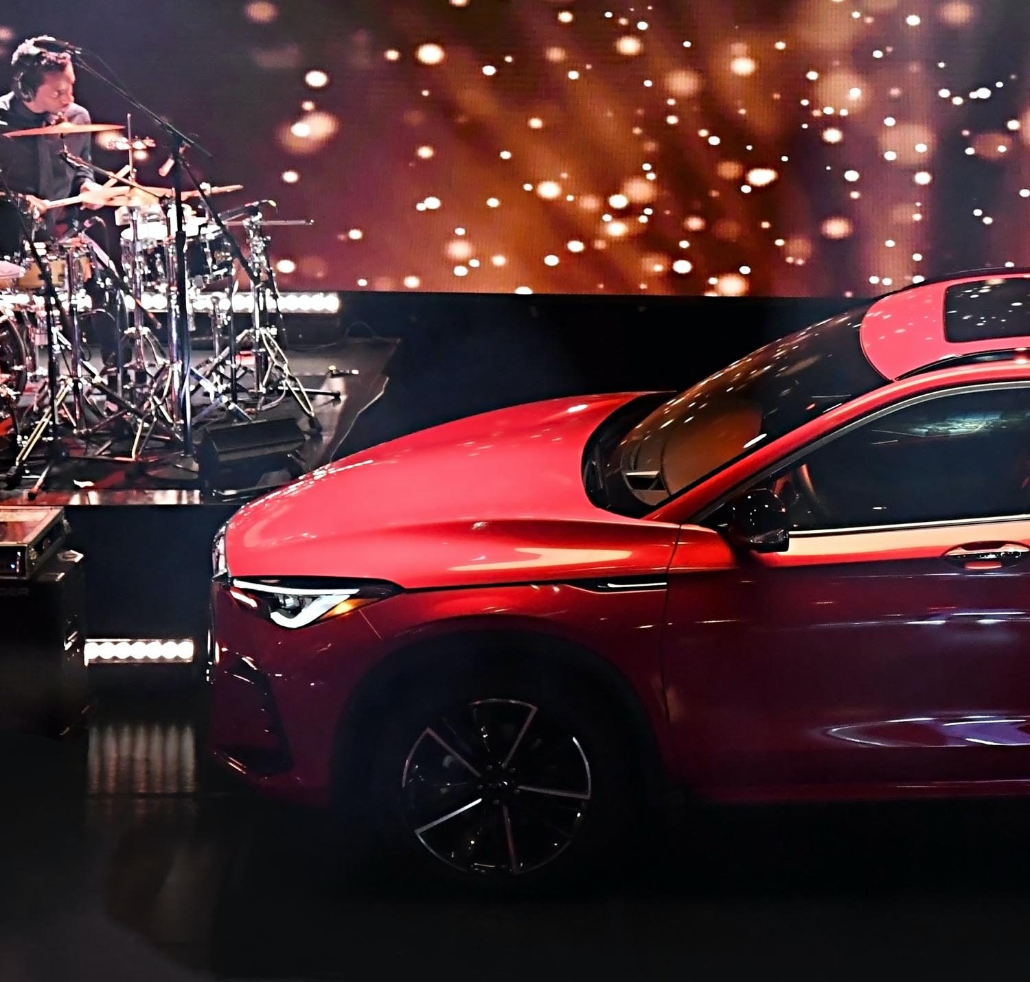 The hood and front of a red new 2022 INFINITI QX55 crossover on stage.