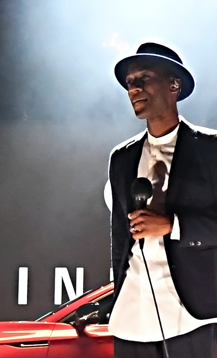 Aloe Blacc holding a microphone on stage during 2022 INFINITI QX55 reveal event