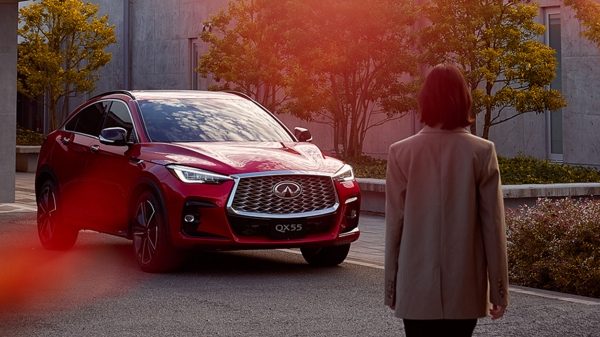Driver walking to a red INFINITI QX55 parked on the street
