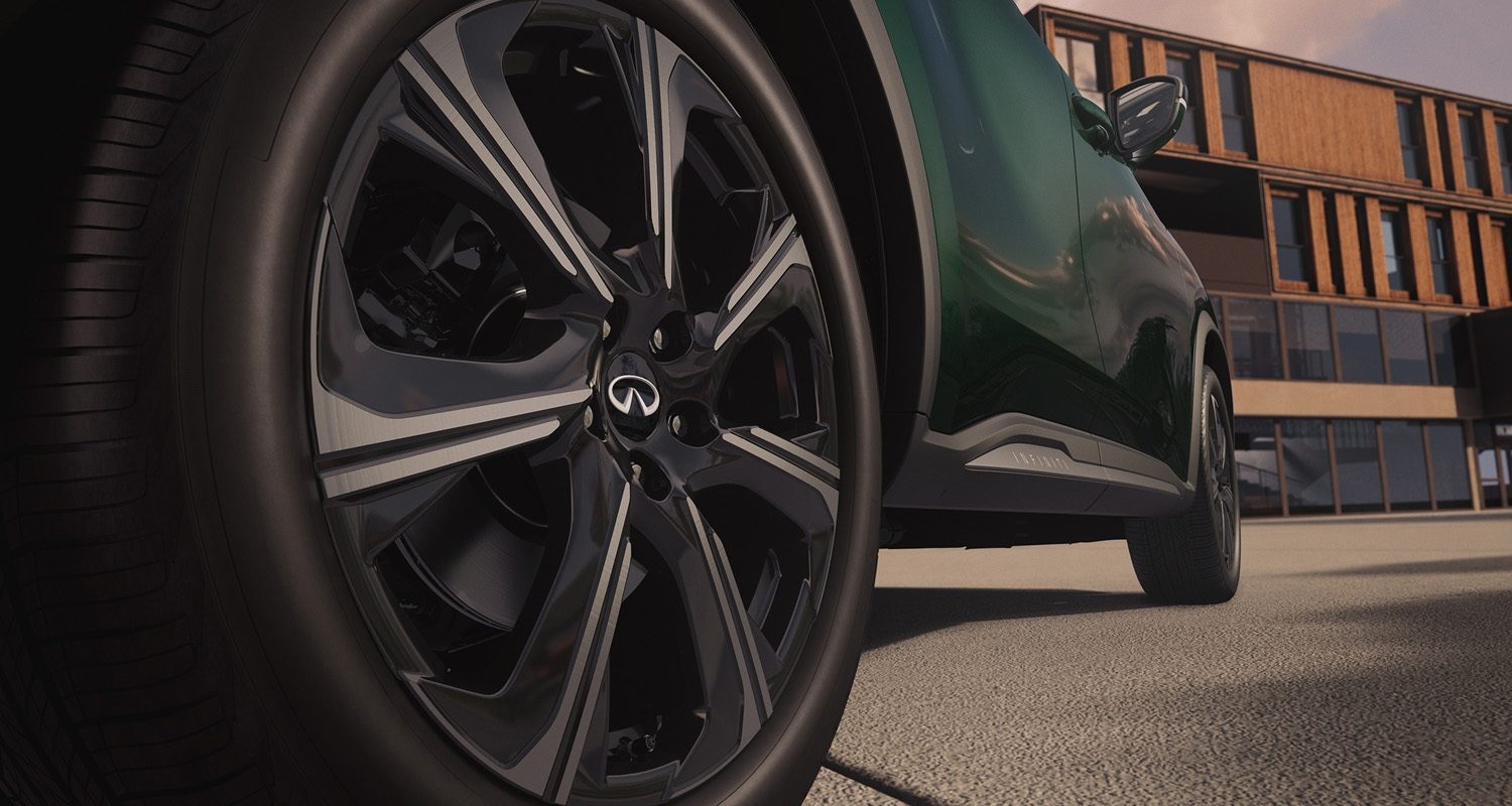 Low-angle shot of new INFINITI QX60 front wheel showing gloss black multi-spoke alloy with brand logo