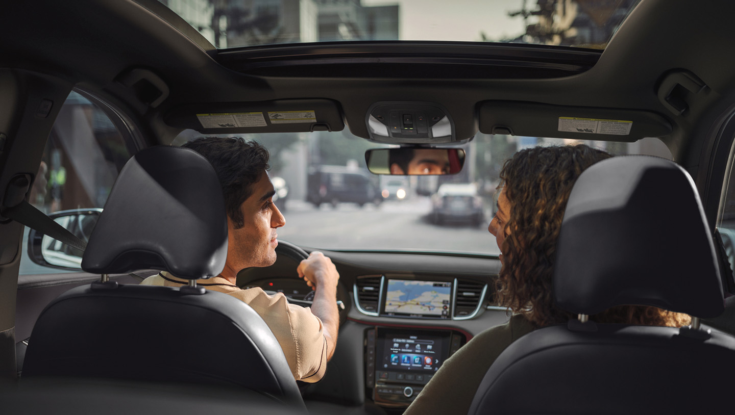 Interior view from back seat of 2025 INFINITI QX50 with driver and passenger conversing