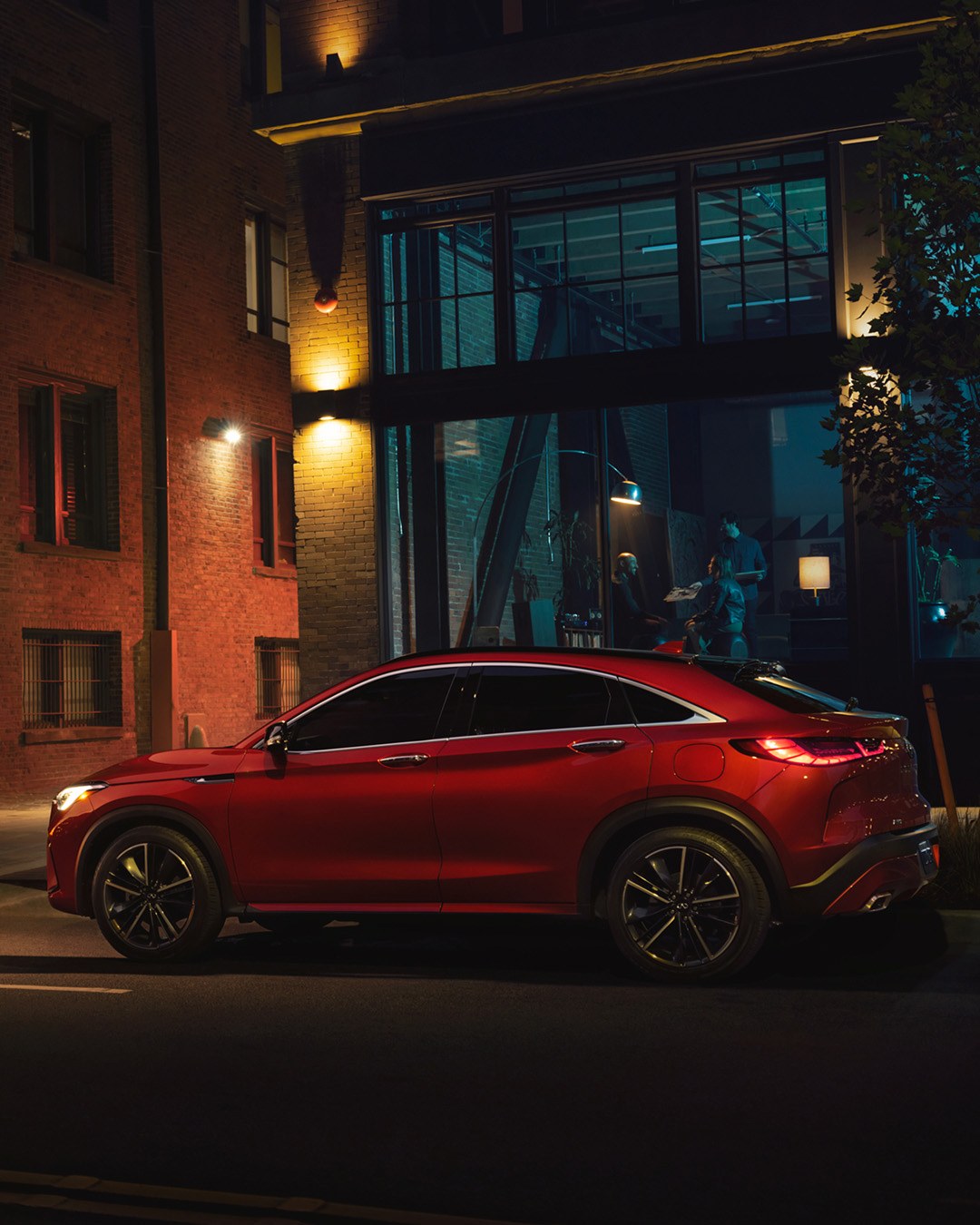 A red INFINITI QX55 crossover coupe parked at night
