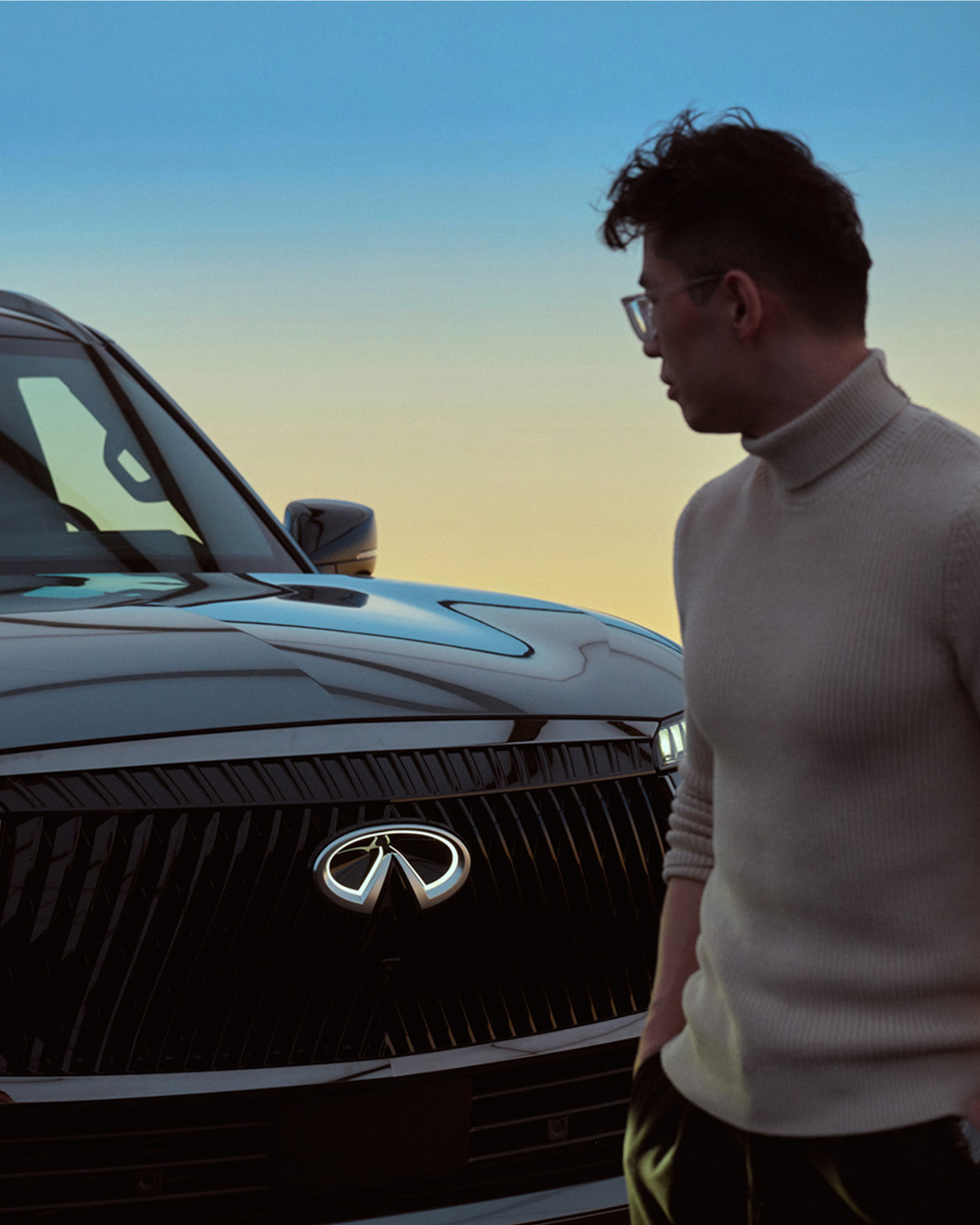 INFINITI owner looking at front of QX80 SUV