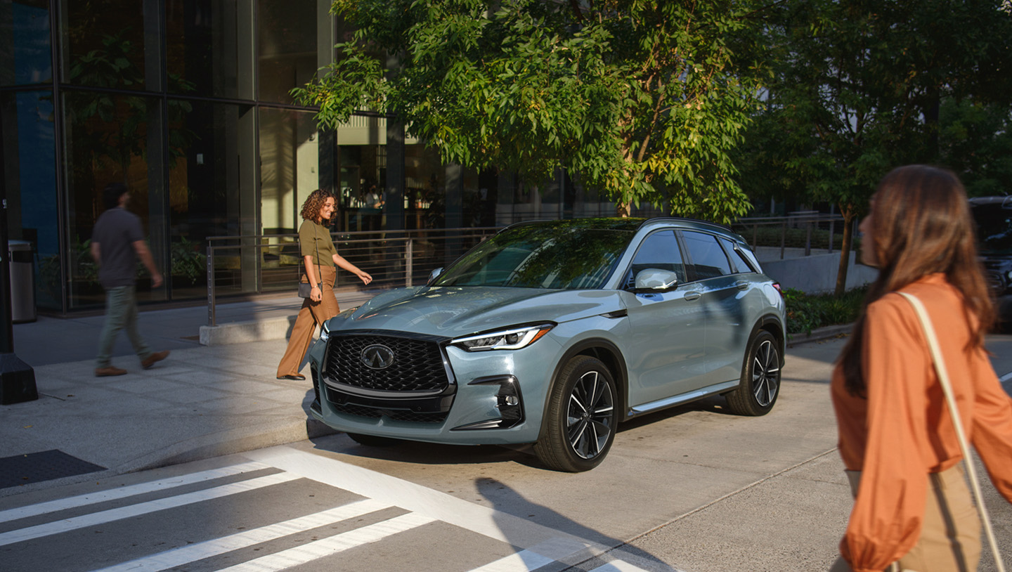 Woman walking towards 2025 INFINITI QX50 luxury compact SUV