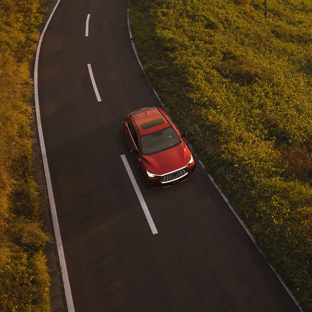 Top view of the INFINITI QX55 driving through autumn roads, showcasing AWD