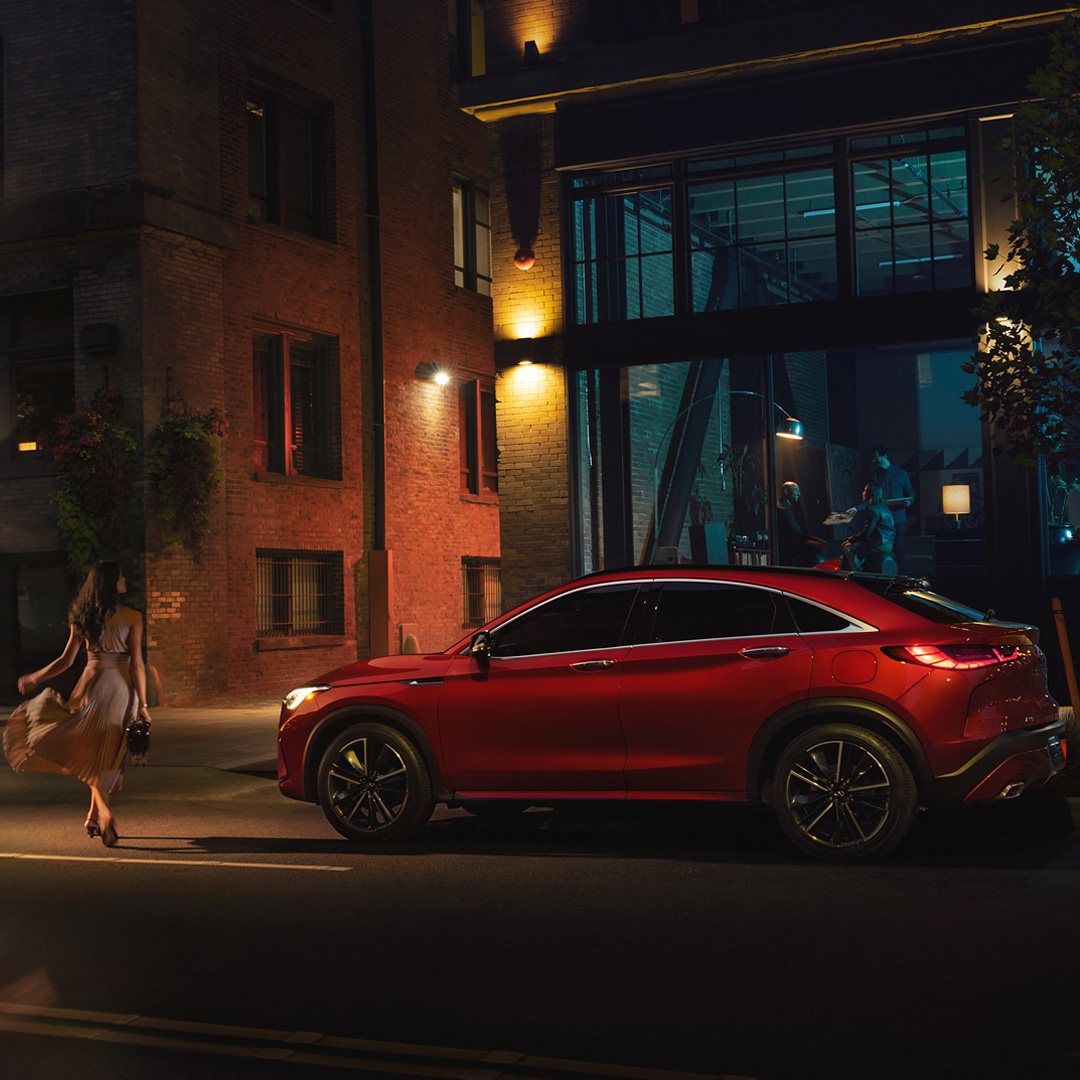 Side profile of INFINITI QX55 with woman walking beside it