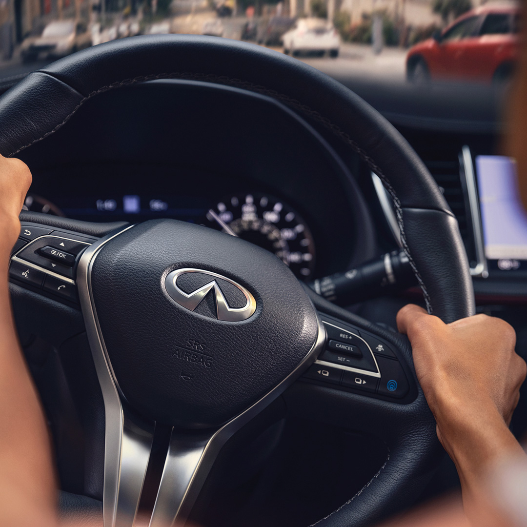 Driver holding QX55 steering wheel with digital dash in view
