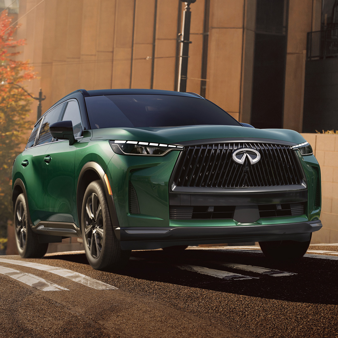 2026 INFINITI QX60 driving through city with high waistline and sculpted body panels