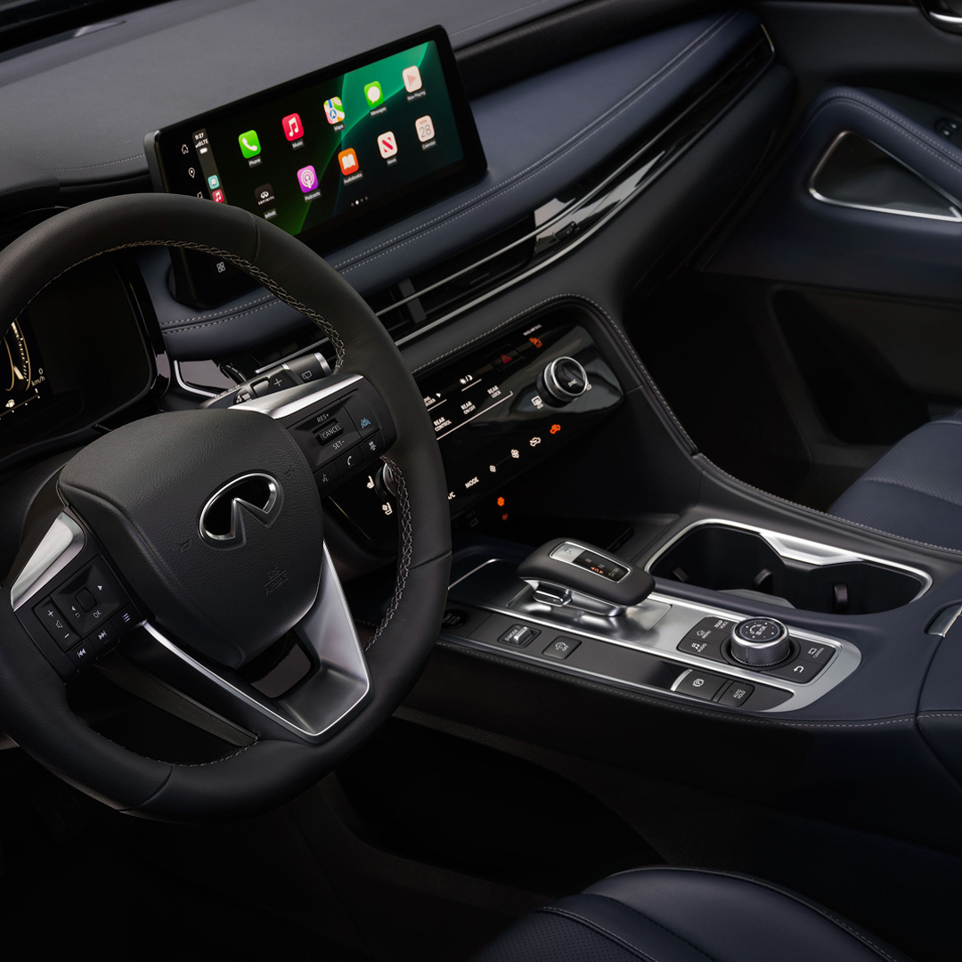 Interior view of 2026 INFINITI QX60 featuring infotainment touchscreen with smartphone connectivity and rotary gear selector