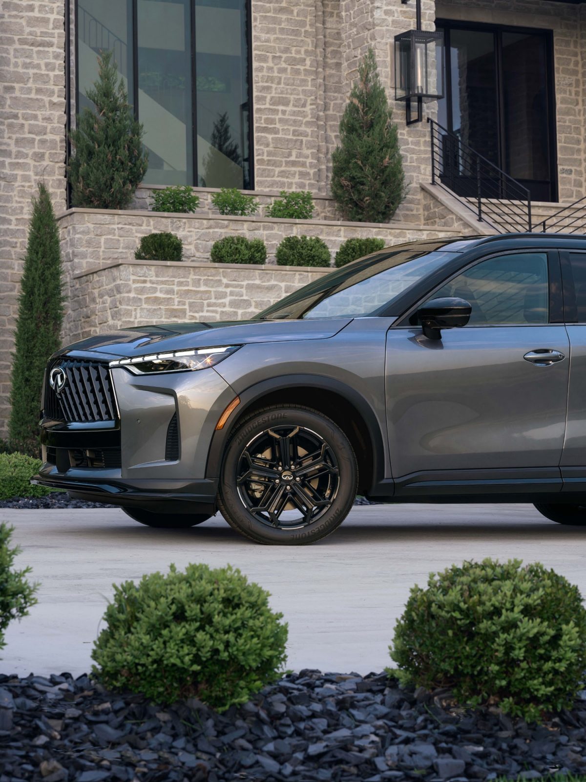 Front quarter view of 2026 INFINITI QX60 featuring gloss black 20-inch alloy wheels in 5-spoke design