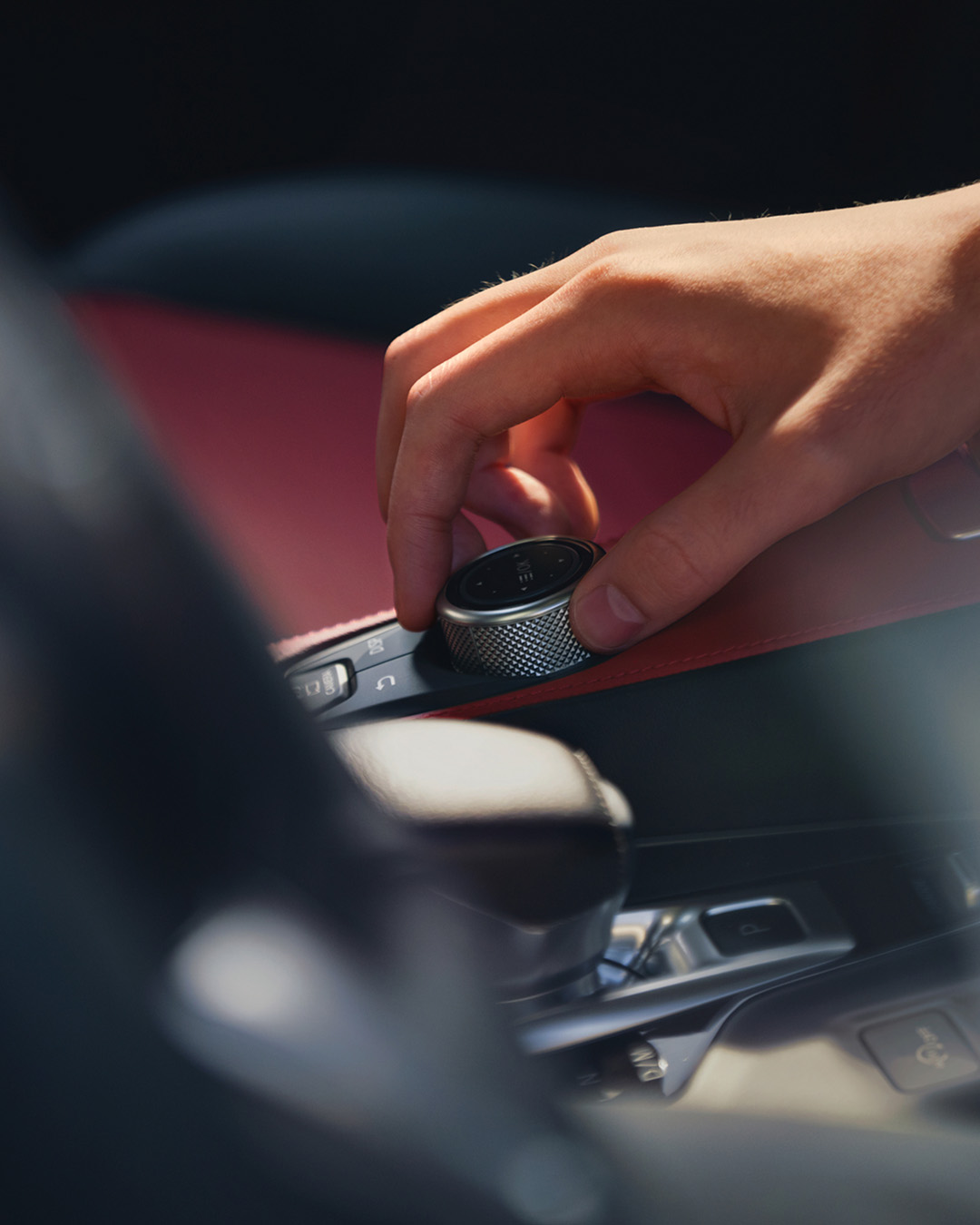 Hand rotating infotainment control knob in INFINITI vehicle cabin