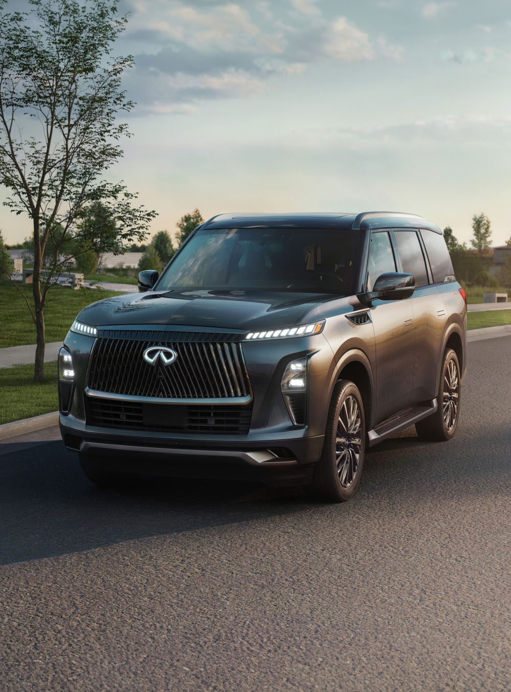 INFINITI QX80 8-seater SUV driving at dusk with signature grille and vertical LED lighting