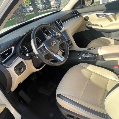 מבט דרך דלת הנהג על המושבים הקדמיים והדשבורד במכונית אינפיניטי QX50