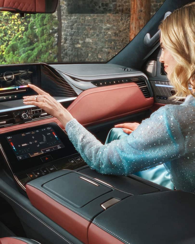 אישה משתמשת במסך המגע המרכזי ברכב אינפיניטי
