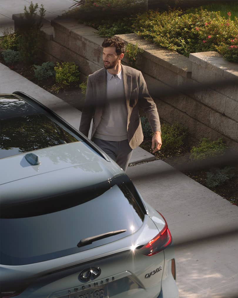 מבט מגבוה דרך חלון על גבר הולך לעבר מכונית אינפיניטי  QX50