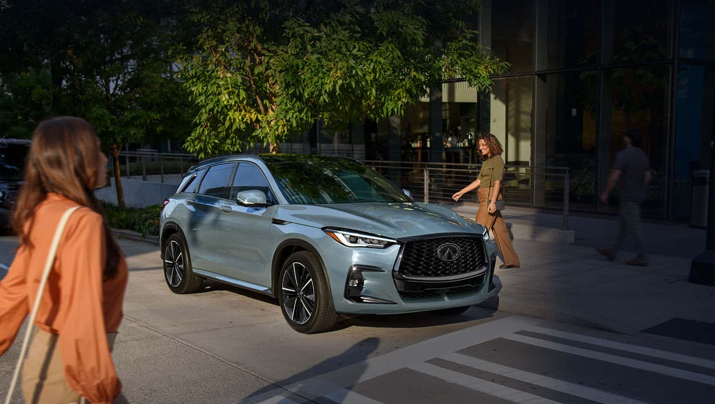 אישה הולכת ברחוב לעבר מכונית אינפיניטי QX50