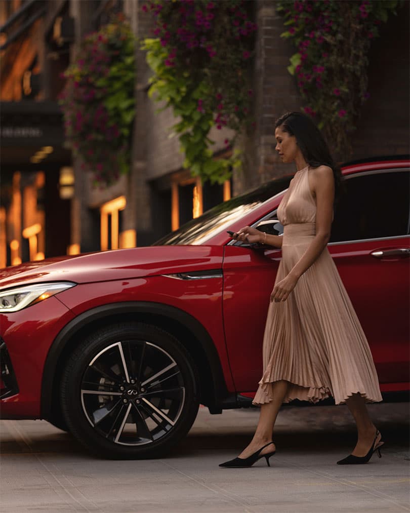 אישה מתקרבת לרכב INFINITI QX55 החונה בעיר ומשתמשת בהתנעה מרחוק