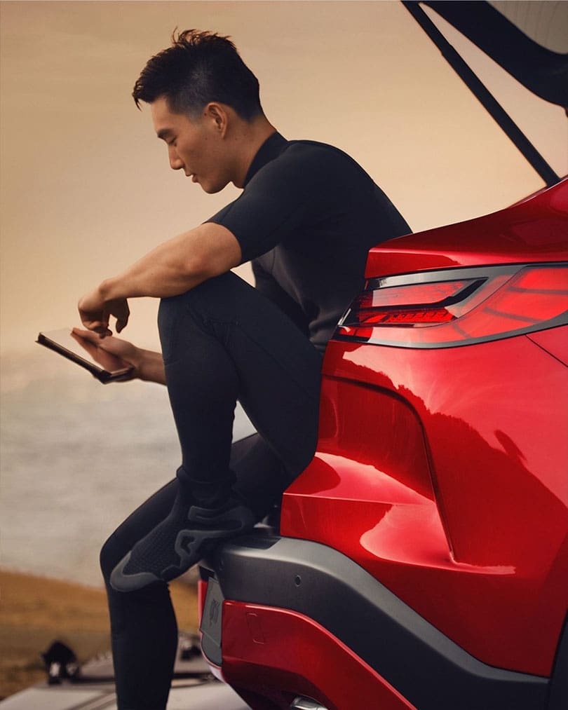 גבר יושב על תא המטען של QX55 ומשתמש בנקודת חמה Wi-Fi