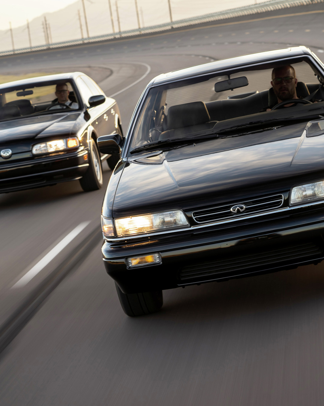 Two black INFINITI Q45 sedans racing on a highway