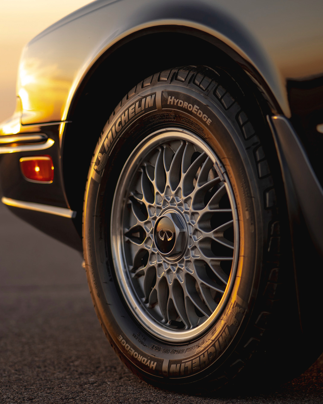 Close-up view of a classic INFINITI car wheel with HydroEdge tire, reflecting the brand's history and craftsmanship
