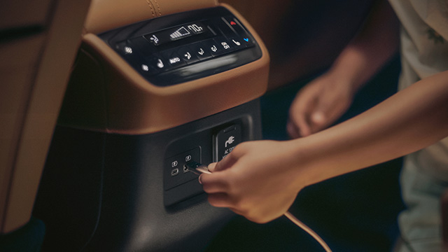 Passenger using USB ports in an INFINITI car, ensuring quick and easy device charging on the go