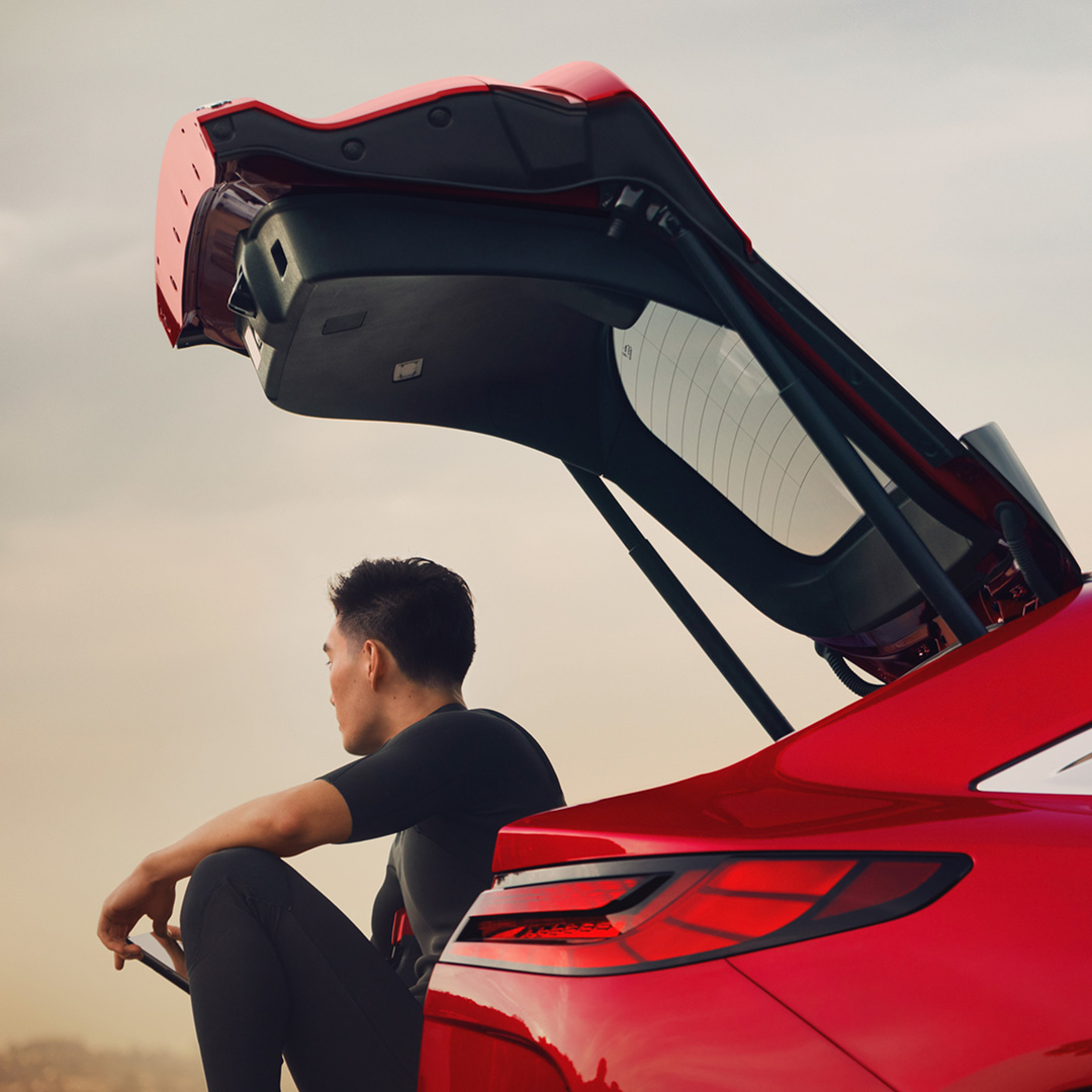 INFINITI car owner sitting on open trunk