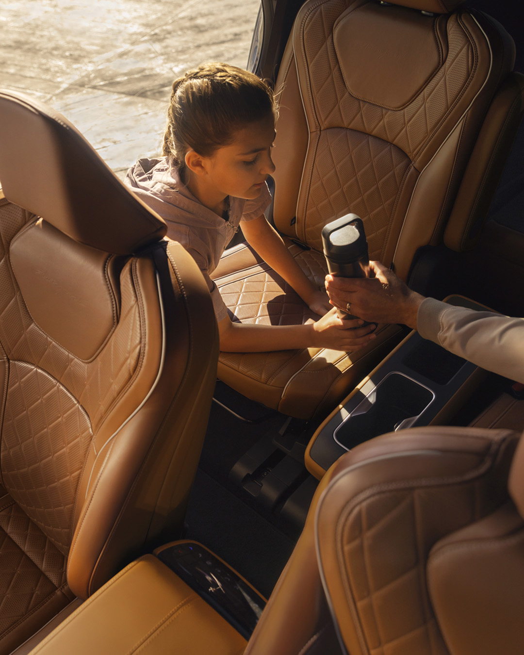Girl taking water bottle from INFINITI car interior
