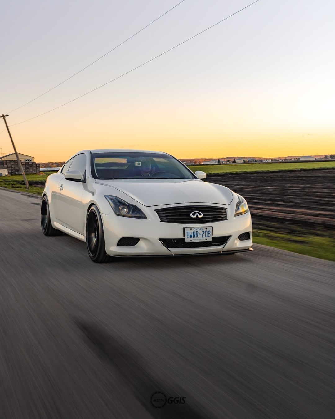 Front view of INFINITI G37 luxury sport sedan driving past field