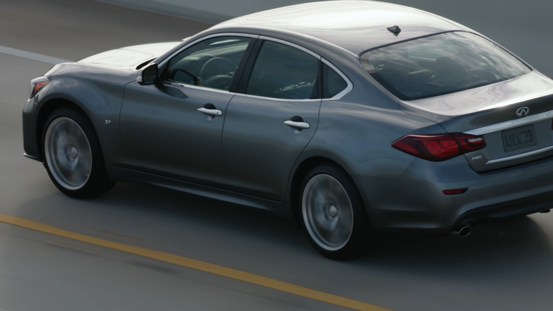 Side profile of silver INFINITI Q70 driving on highway