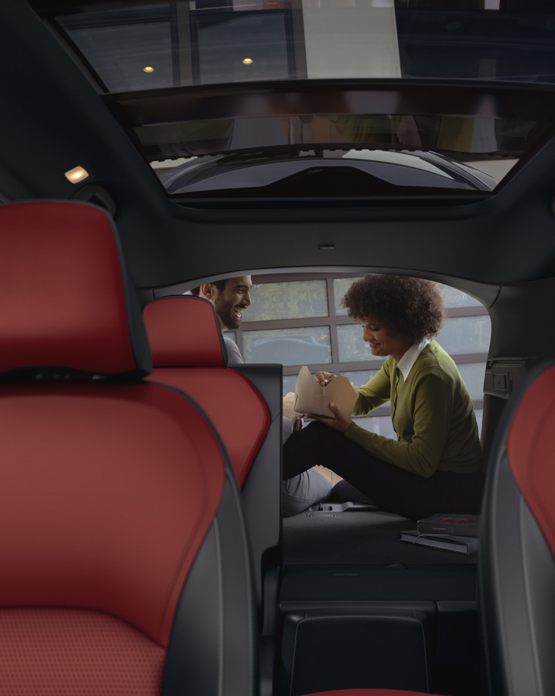 Interior view of INFINITI owners sitting in cargo space and eating takeout food 