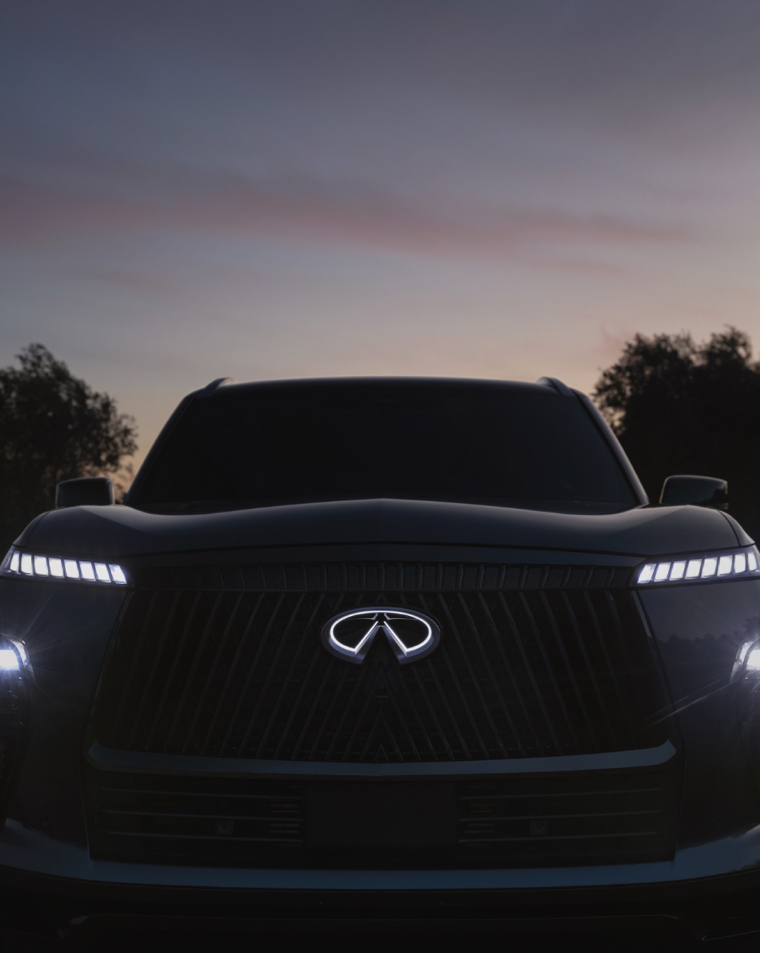 Front view of INFINITI vehicle parked in front of sunset