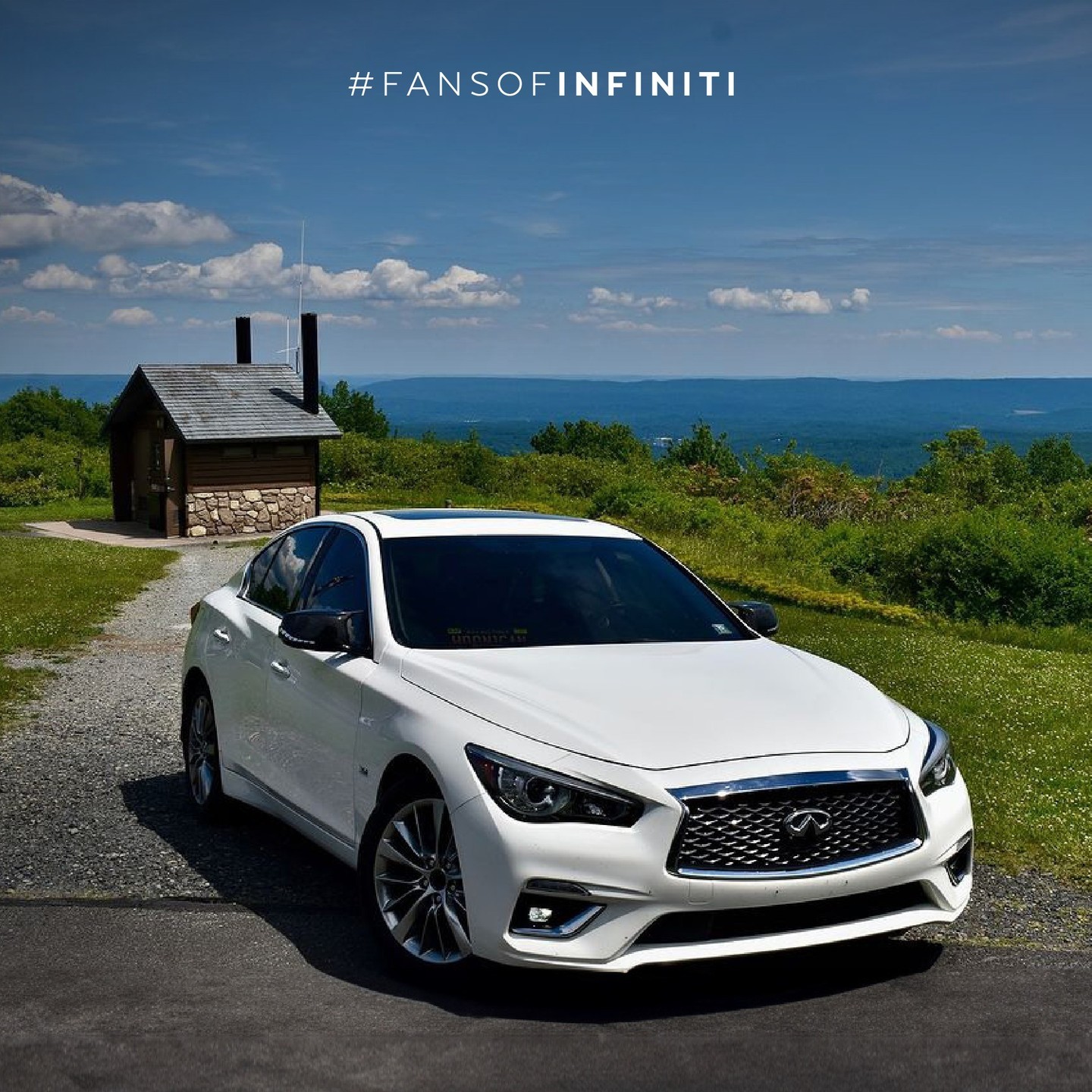 White INFINITI Q50 parked by the ocean under blue skies