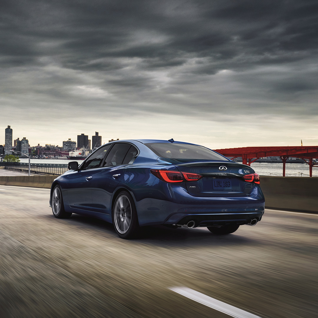 Blue Q50 sedan driving across a bridge