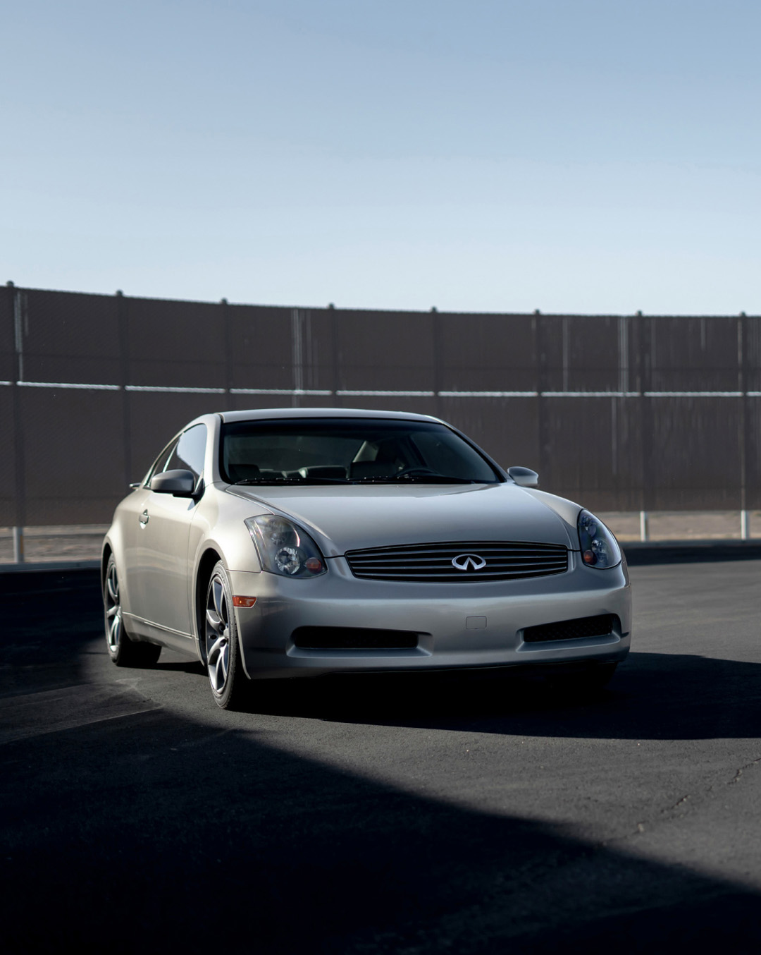 Silver INFINITI G35 parked in front of fence
