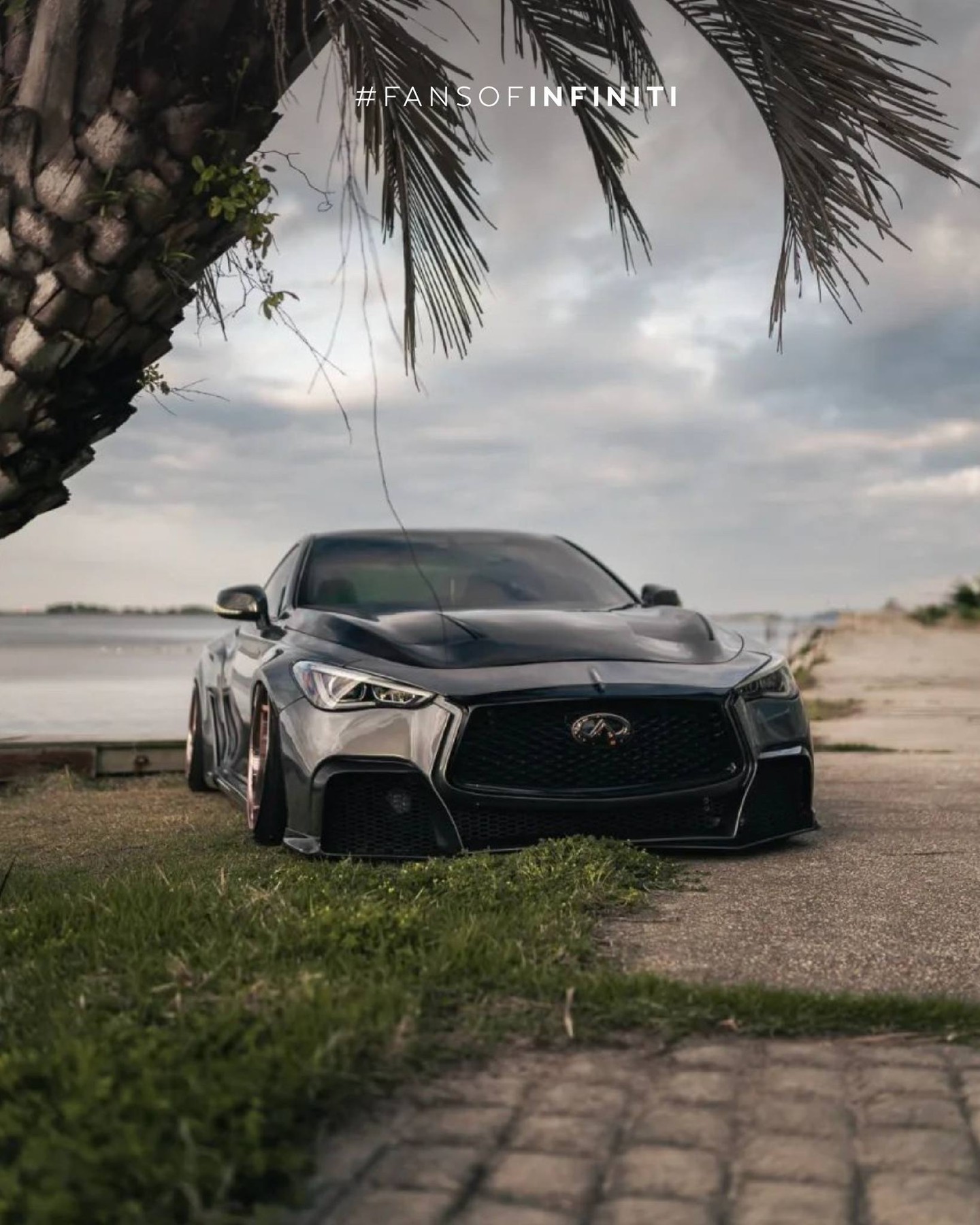 INFINITI Q60 parked on beach in front of palm tree