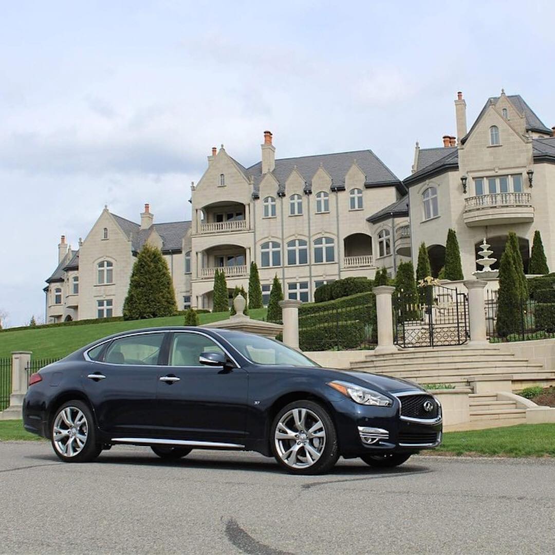 INFINITI Q70 luxury sedan parked in front of mansion