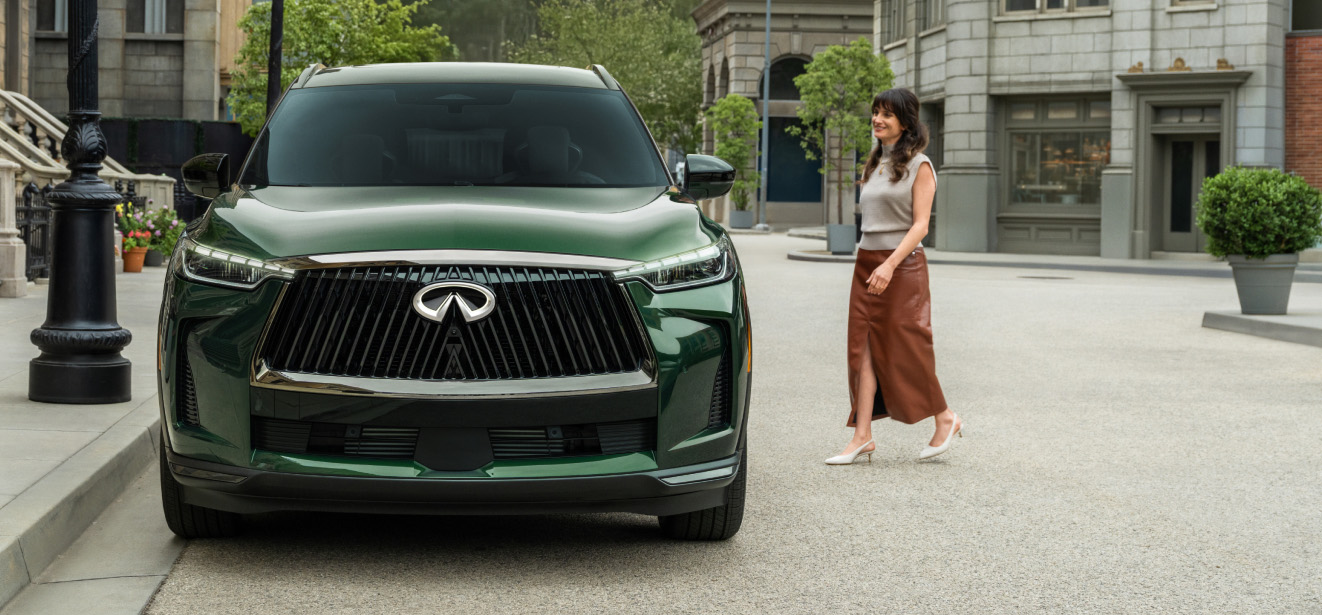 Front view of INFINITI QX60 parked on city street with woman approaching