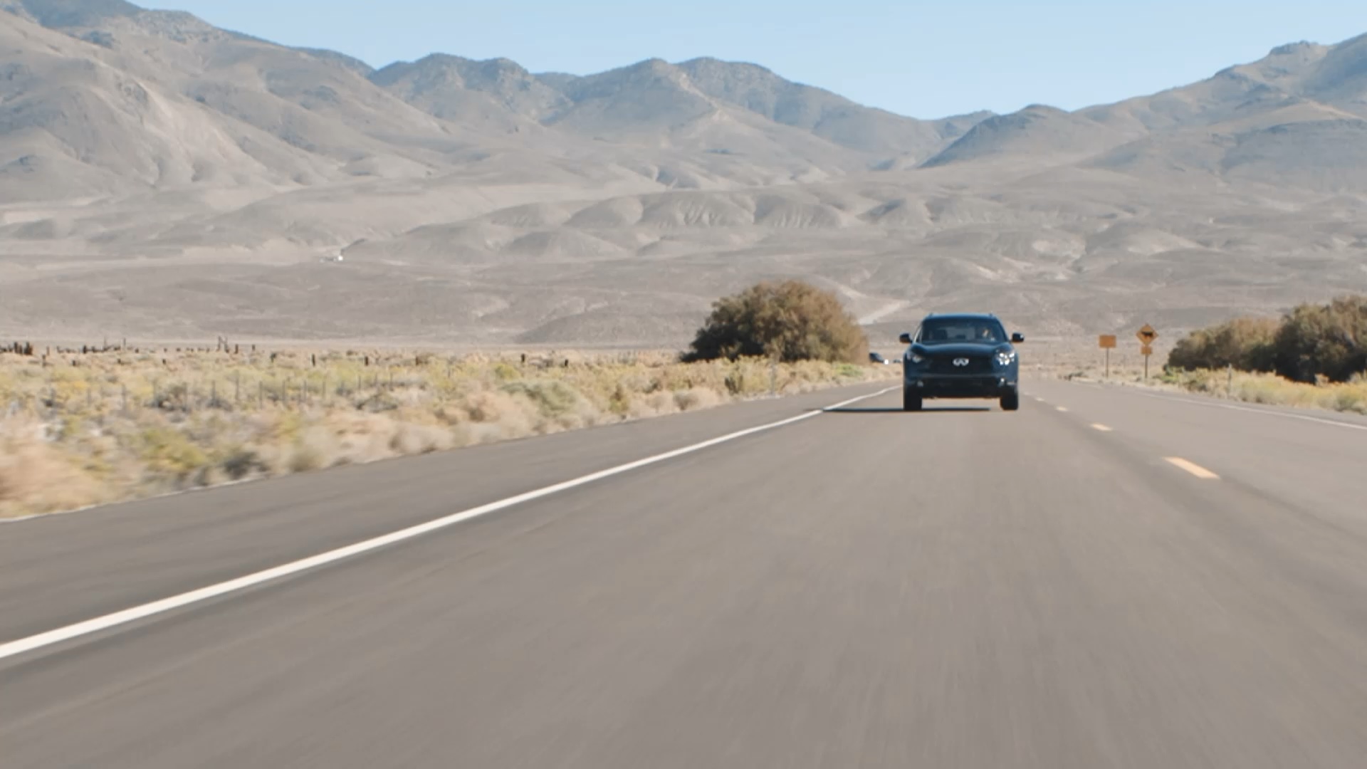 Front view of INFINITI QX70 Luxury Crossover SUV driving through desert