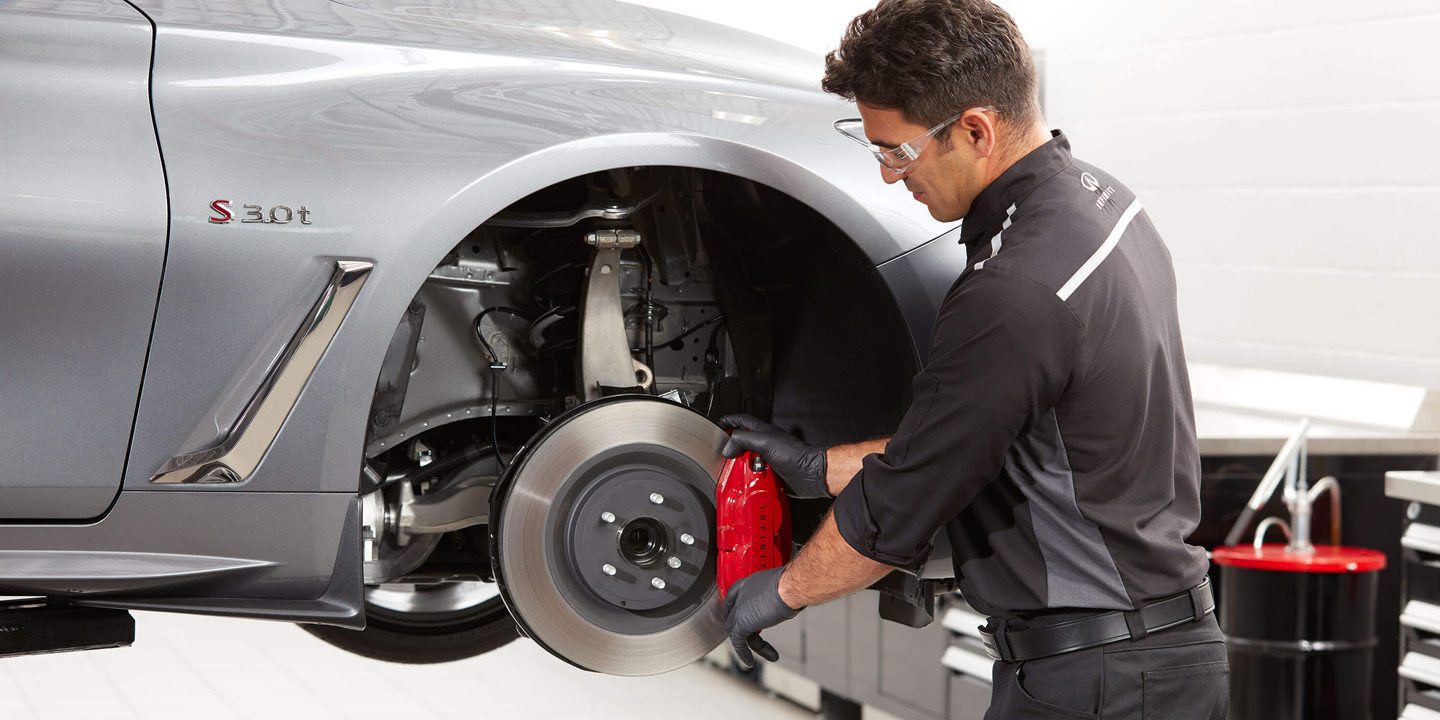 An auto repair mechanic fixing the wheel of a 2022 INFINITI vehicle.